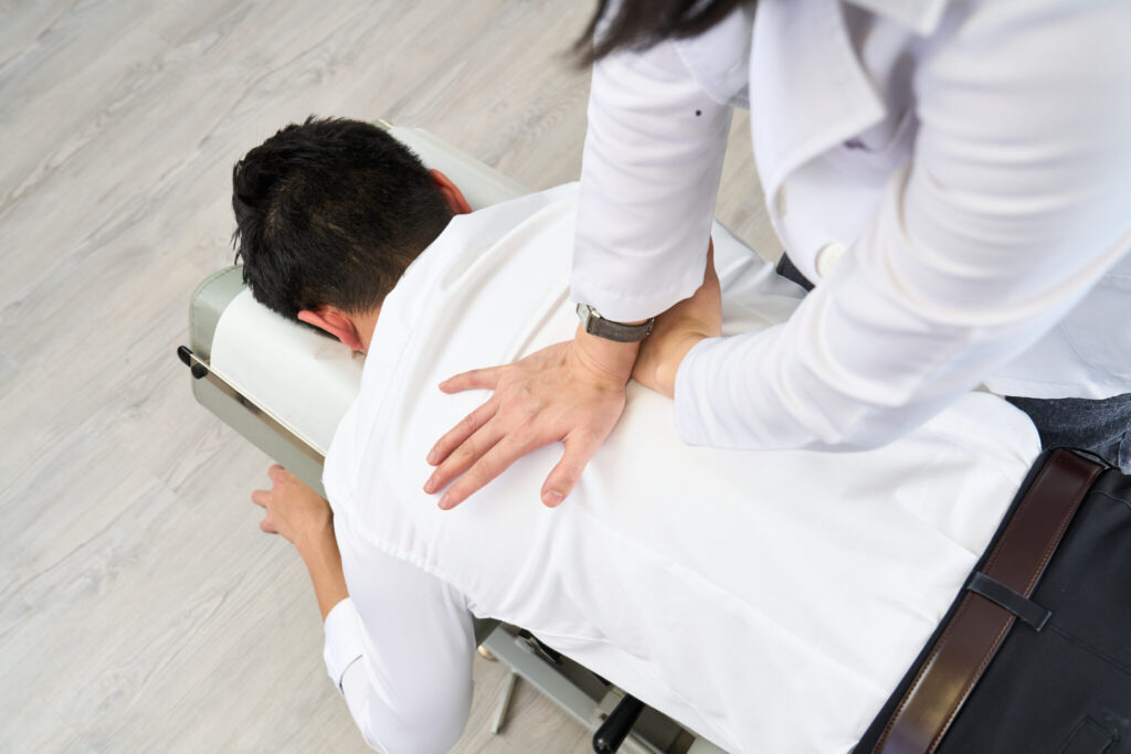 Chiropractor assessing a patient's back and hip after a hiking injury in Hong Kong